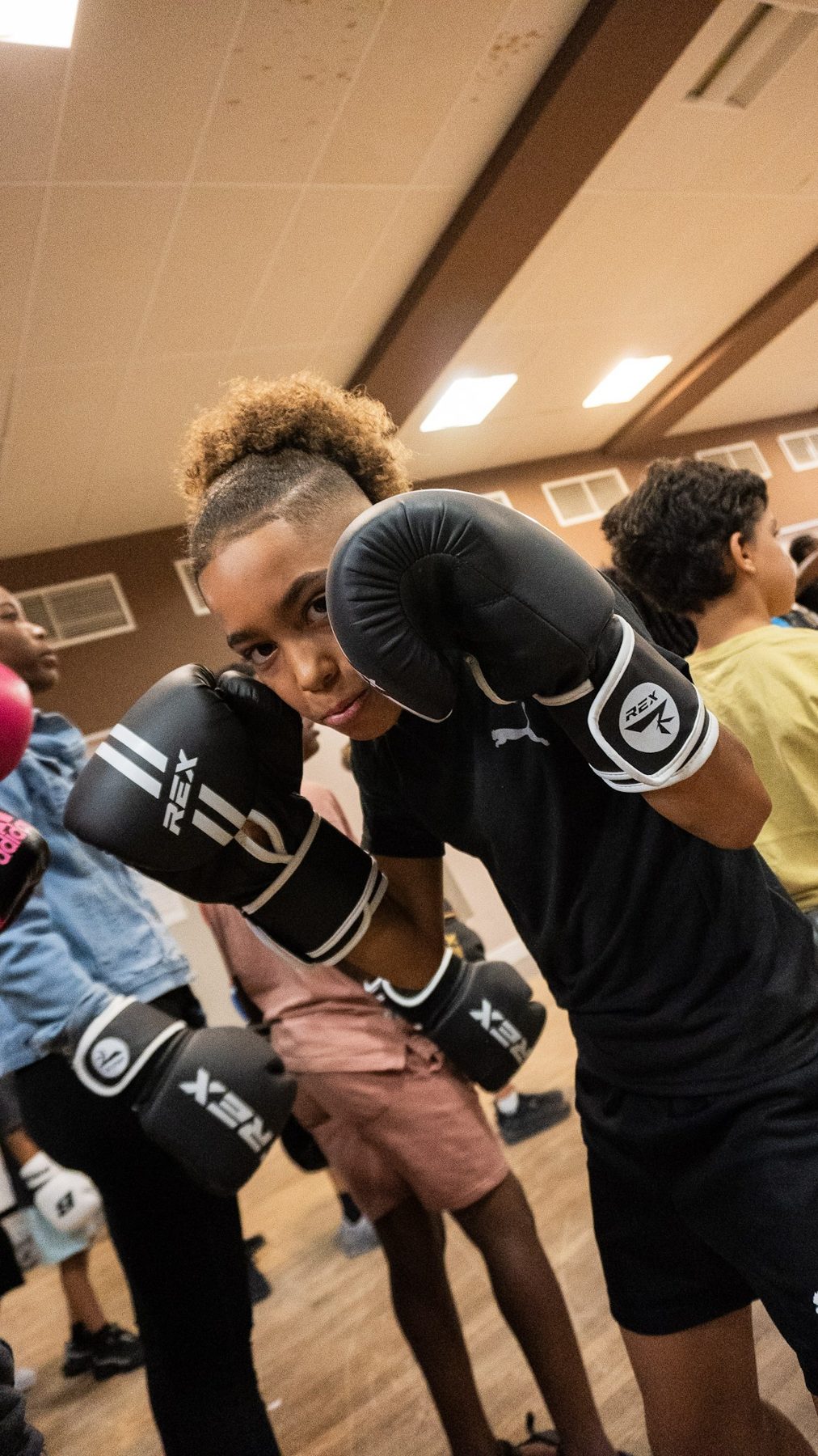 Young participant in boxing gloves holding a guard during a ClockiT session