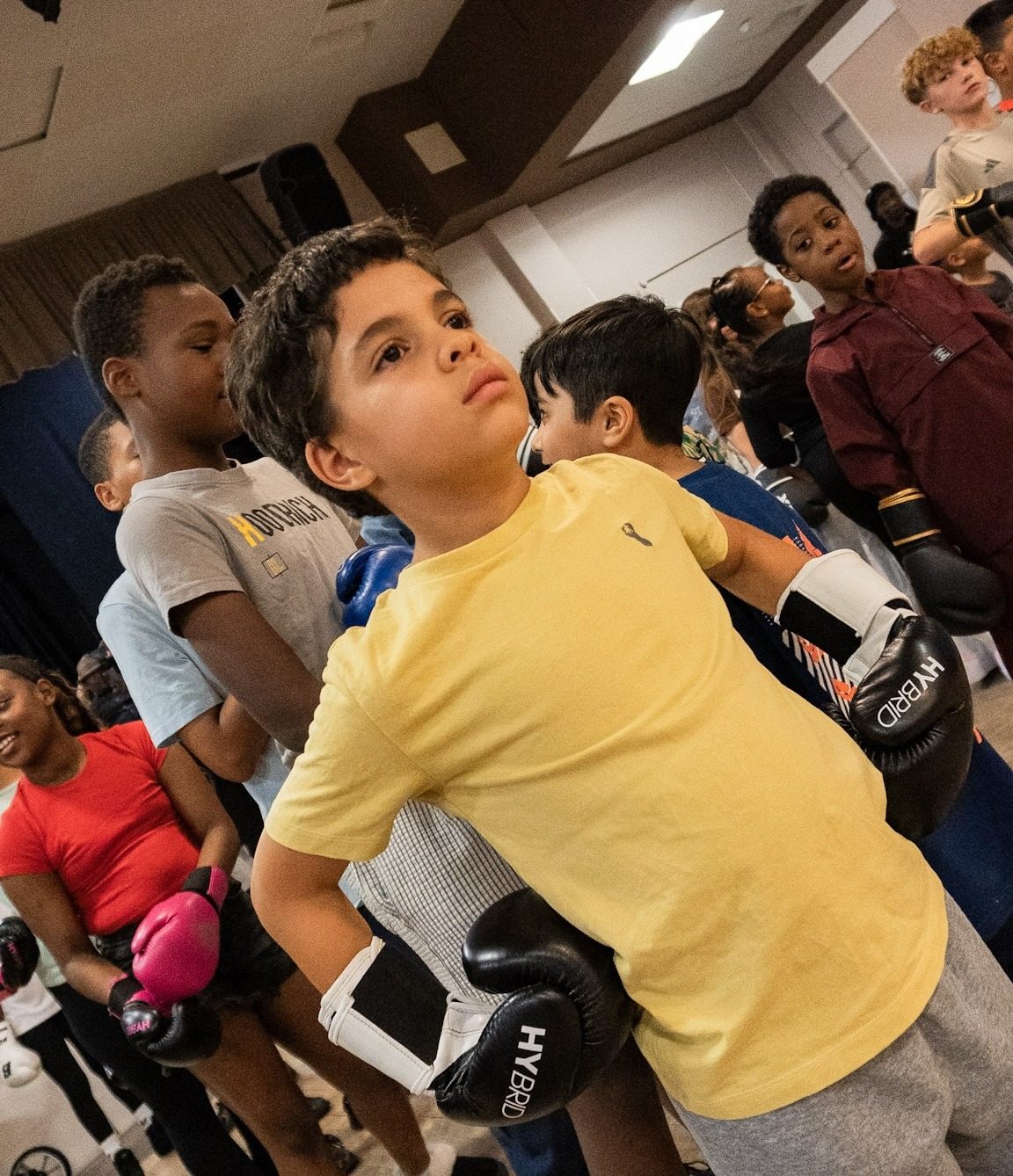 Young person in a yellow t-shirt wearing boxing gloves at a ClockiT session